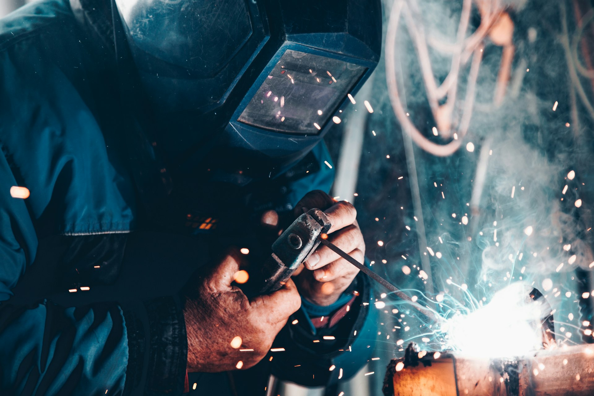 Industrial welder at work, sparks flying in a dark factory environment
